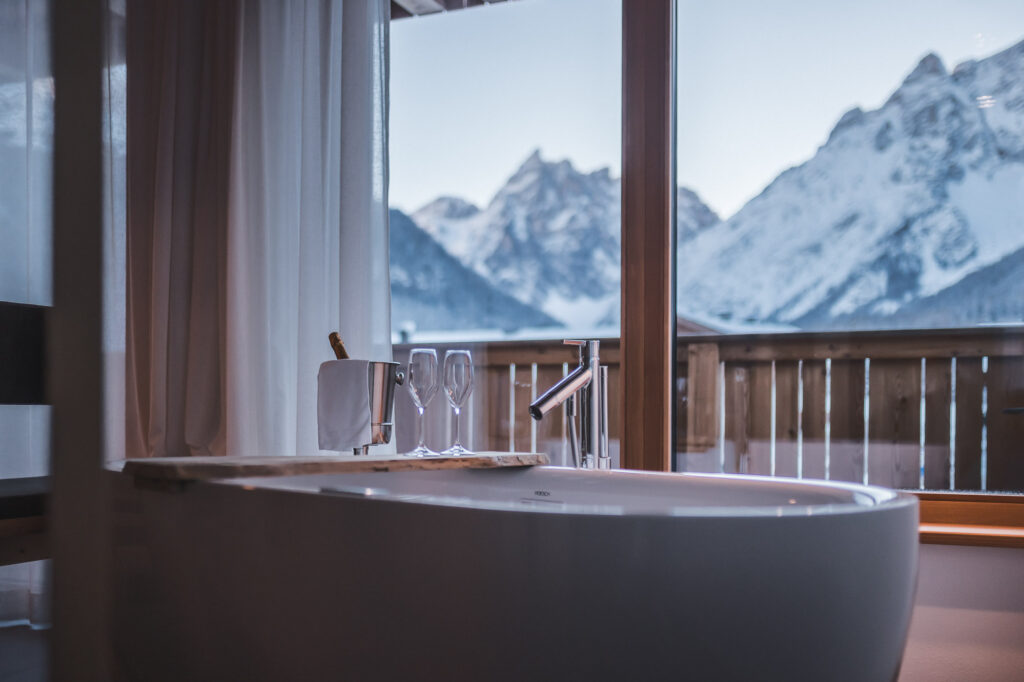 Aussicht von der freistehenden Badewanne auf die verschneiten Bergspitzen im Apartment Gänseggile
